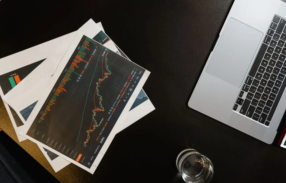 about-us-02 Person analyzing business charts with smartphone and laptop on desk.
